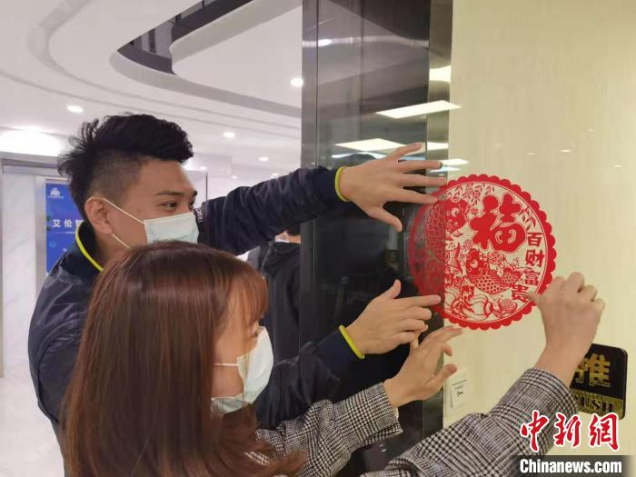 台湾青年夫妇刘宗鑫和林俞青一同将窗花“福”字贴在了基地门口。　郑江洛 摄